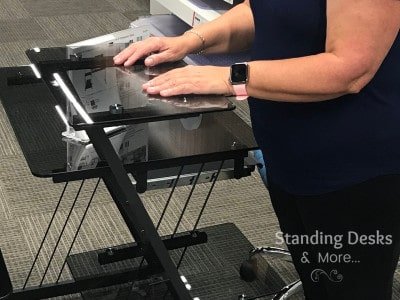 Stand in front of the standing desk and rest your elbow at a 90-degree angle.